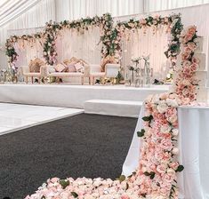 a wedding ceremony setup with flowers on the floor and white linen draped walls behind it