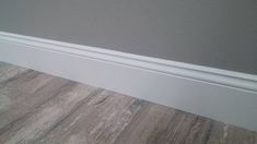 the corner of a room with wood flooring and white trim on the wall above it