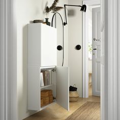 an open door leading into a white room with bookshelves and shelves on the wall