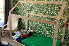 a wooden bed frame with stuffed animals on it in front of a green wallpapered room