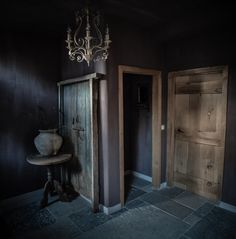 an empty room with two wooden doors and a chandelier