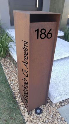 a large metal sign sitting on top of a gravel field next to a door way