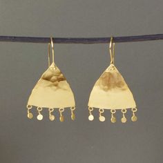 A stunning and unique pair statement Moroccan style drop earrings are handmade in a rustic Moroccan style in 18ct gold plated sterling silver. These lovely earrings have a distinctly Moorish feel to them. Softly beaten and smoothed and given a subtle matte finish that glistens subtly as it catches the light, these eye-catching earrings are accentuated, each with five beaten discs that hang from the bottom and move with the wearer. Each earring has an overall drop of approximately 5cm and is hand Gold Hammered Long Drop Jewelry, Artisan Gold Long Drop Earrings, Gold Long Drop Artisan Earrings, Gold Hand Forged Drop Earrings, Artisan Long Drop Gold Jewelry, Hand Forged Gold Drop Earrings, Gold Hammered Sterling Silver Earrings, Artisan Hammered Drop Earrings, Hammered Yellow Gold Long Drop Jewelry