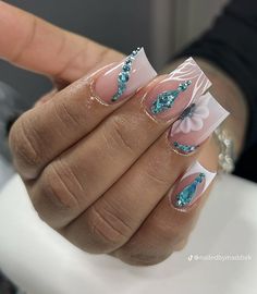 a woman's hand with blue and white nail polish on it, holding onto the tip of her finger