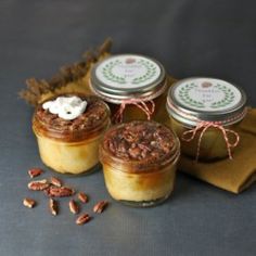 three jars filled with food sitting on top of a table next to a napkin and some nuts