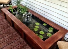 a wooden bench sitting on top of a wooden deck next to a planter filled with water