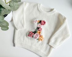 The perfect first birthday outfit, embroidered with flower colors of your choice.  *If you're looking for a specific sweater or yarn color, please send me a message and I can source it for you. TO ORDER -Select size and sweater color via the drop down menus -In the personalization box, please leave the desired flower colors (leaves are included in two shades of green) SIZING AND FIT -All sweaters are an OVERSIZED fit, perfect for watching baby grow throughout their first year, layering, or having a long lasting, heirloom piece. If you'd like a more snug fit, order a size down. WASHING INSTRUCTIONS: Turn sweaters inside out before washing on delicate, and lay flat to dry. **This product is handmade and hand embroidered. No two are exactly the same and are custom  made. Sizing and exact colo Birthday Sweater, Outfit Birthday, Flower Colors, First Birthday Outfit, Baby Grow, First Birthday Outfits, Embroidered Sweater, Photoshoot Outfits, Birthday Photoshoot