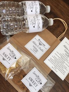 two bottles of water and some snacks on a wooden table with labels for each bottle