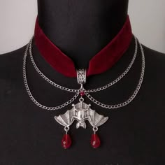 Unveil your darkly elegant side with our "Gothic Enchantment: Crimson Velvet Choker with Midnight Bat Pendant." This exquisite piece is a captivating blend of gothic allure and mystic charm, designed for those who revel in the enigmatic and the beautiful. Crafted with the finest crimson velvet, the choker sits gracefully around your neck, offering a luxurious touch that is both comfortable and mesmerizing. The velvet's deep red hue evokes a sense of vintage romance and dark sophistication, making it a perfect accessory for gothic enthusiasts and fashion-forward individuals alike. Suspended from the choker is a meticulously designed bat pendant. Cast in high-quality metal with an intricate level of detail, the bat symbolizes the mysterious night and its untold stories. The pendant's dark fi Gothic Bedding, Alternative Accessories, Vampire Vibes, Vampire Jewelry, Goth Things, Weird Jewelry, Velvet Choker Necklaces, Vampire Aesthetic, Gothic Chokers