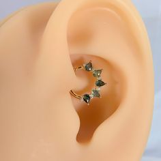 a pair of ear piercings with green crystals