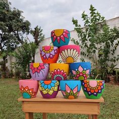 colorful bowls are stacked on top of each other in front of a fenced area