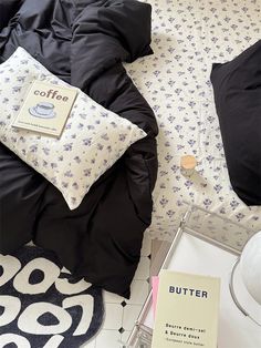 a bed with black comforter and pillows on top of it next to a book