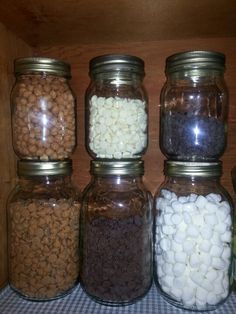 four jars filled with different types of beans and marshmallows on a checkered table cloth