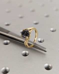 a gold ring with a black diamond sits on top of a pair of scissors