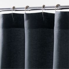 black curtains hanging on a metal rod in front of a white wall and window curtain