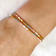 A delicate double wrap silk bracelet with teal, golden orange, tan and off white glass beads with a sliding clasp to adjust to your size. As part of the California Dreaming collection the San Clemente bracelet is a nod to the colours of 1960's vintage surf towns of Southern California and their laid back vibes. On a natural beige silk cord with high quality tiny Japanese glass beads and 14k gold filled sliding clasp and beads. This bracelet is super lightweight and easy to put on and so comfy you'll forget you're wearing it! Fits an average wrist size of up to 7 inches and tightens to 6.25in. Extends to maximum of 8.5in to fit over the widest part of the hand. If you have a smaller or larger wrist and hands and would like a custom size please contact me. Displayed in one of our pretty gift Silk Cord Bracelet, Silk Bracelet, Beige Silk, Boho Jewellery, Hippie Bracelets, Vintage Surf, San Clemente, Teal Orange, Silk Cord