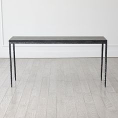 a black table sitting on top of a hard wood floor next to a white wall