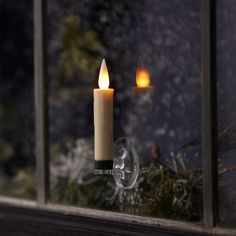 two lit candles sitting on top of a window sill