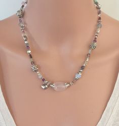 "An evocative and playful necklace that features a small puffy silver tone heart alongside a barrel-shaped Rose Quartz stone.  This necklace has many gemstone accents including Clear Quartz, Red Garnet, Fluorite, Ruby, Amethyst, Pearls and Chyrsoprase. This necklace is 18.5\" in length and has a 3\" Sterling Silver extender chain.  You can wear this necklace long, short or as a multi-wrap bracelet. It has Silver tone beads, Sterling Silver beads with Sterling Silver findings. NM Jewelry Design offers one-of-a-kind and limited edition jewelry. My creations are feminine, sophisticated and inspired by the cultures that traded along the ancient Silk Road. I am a Certified Gemologist and Accredited Jewelry Professional.   Please contact me for more information about the other necklaces shown in Silver Heart-shaped Gemstone Beads Jewelry, Silver Heart Jewelry With Gemstone Beads, Silver Heart-shaped Jewelry With Gemstone Beads, Briolette Necklace, Multi Wrap Bracelet, Carnelian Necklace, Citrine Earrings, Rose Quartz Necklace, Rose Quartz Stone