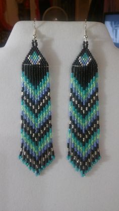 two pairs of beaded earrings are displayed on a white display stand, one is blue and the other is green