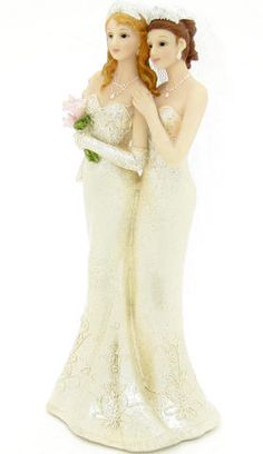 two brides figurines standing next to each other with flowers in their hands