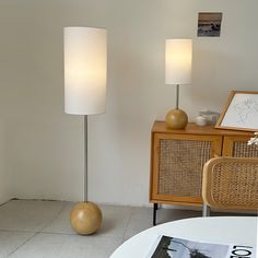 two lamps sitting next to each other on top of a white tiled floor near a table