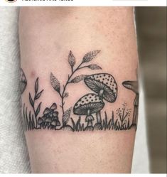 a black and white mushroom tattoo on the left leg with plants growing out of it