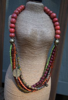 Multi-strand tribal necklace in African trade beads. Old red Olumbo beads make up the upper portion of this design, accented with primitive African brass rounds and rings. The six strands of smaller Indonesian glass beads and dark red Prosser beads flow colorfully to form the lower half, punctuated with Fulani and Yoruba brass pieces. This necklace is truly a joyful blend of colors and textures, so much that I am tempted to hang onto it and wear it myself. The closure is an unusual artisan solid brass toggle befitting the tribal style of this piece. Length is 24 inches, and it is a bit heavy with all those beads. Your package will come to you gift wrapped in natural, and environmentally friendly materials. All my jewelry is 100% workmanship guaranteed. Any problem with construction or comp Trade Bead Jewelry, African Trade Bead Jewelry, African Trade Beads, African Style, Trade Beads, Multi Strand Necklace, Necklace Vintage, Strand Necklace, Multi Strand