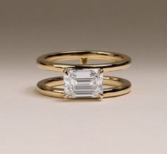 two gold rings with an emerald cut diamond