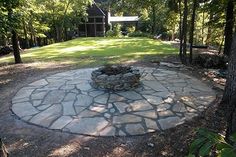 a stone fire pit surrounded by trees and grass