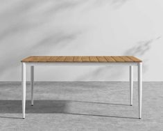 a wooden table with white legs and a wood top on concrete floor in an empty room