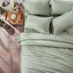 an overhead view of a bed with green sheets and pillows on it, along with potted plants