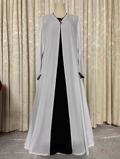 Snow white and black abaya burqa 3-piece set with matching hijab/scarf in high quality fabric, summer friendly, and suitable for all weather conditions.  Abaya white upper cape and hijab is handmade in soft, lightweight, breathable abaya fabric pipened with rich black borders matching under abaya and single button closure Black under abaya is handmade in super soft cotton linen fabric, full sleeved with zippered side pockets and pearl neck button.  Abaya cape and under abaya are detachable, may be worn together or separately, as per choice. Super soft cloth and a simple stylish look. Available in size 52. Long Niqab For Eid, Elegant Long Niqab For Eid, White Niqab For Eid, Elegant White Wedding Khimar, Elegant Long White Khimar, Elegant White Abaya For Formal Occasions, Elegant White Formal Abaya, Elegant Long White Abaya, Fitted Long Abaya With Dabka Details