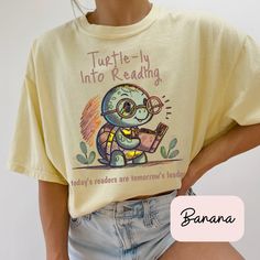 Celebrate the joy of reading with our Comfort Colors 1717 T-Shirt, featuring the delightful saying, "Turtle-ly Into Reading, Today's Readers, Tomorrow's Leaders." This charming design, showcasing a cute turtle engrossed in a book, is perfect for elementary school teachers, reading teachers, and book lovers who inspire young minds every day. Key Features: Premium Comfort: Crafted from 100% ring-spun cotton, the Comfort Colors 1717 T-Shirt provides a soft, relaxed fit that feels great from the ver Motivational Teacher Shirts, Bookish Crew Neck T-shirt With Letter Print, Summer Bookish T-shirt With Letter Print, Bookish Short Sleeve T-shirt With Funny Text, Summer Graphic Print Bookish T-shirt, Bookish Crew Neck T-shirt With Funny Print, Bookish T-shirt With Funny Print And Short Sleeves, Relaxed Fit Pre-shrunk Bookish T-shirt, Bookish T-shirt With Funny Print For School