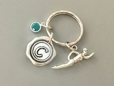 a metal key chain with a silver and green charm