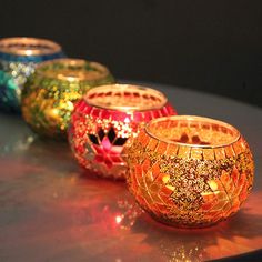 three colorful glass candles sitting on top of a table next to each other and one candle in the middle