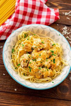 pasta with chicken and parsley in a blue and white bowl on a wooden table