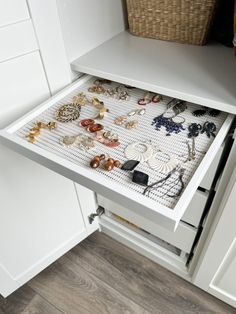 an open drawer in a white cabinet filled with jewelry