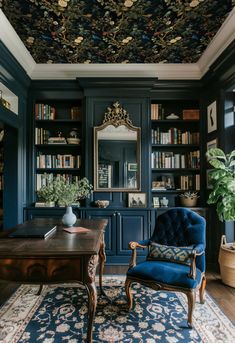 a blue chair sitting in front of a wooden table on top of a rug next to a bookshelf