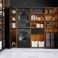 a washer and dryer sitting in front of wooden shelves filled with laundry items