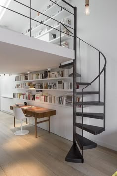 a spiral staircase in the middle of a room with bookshelves on either side