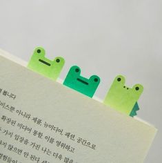 three little green frog magnets sitting on top of a piece of paper with chinese writing