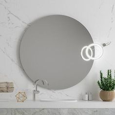 a bathroom with a round mirror on the wall and a potted plant next to it