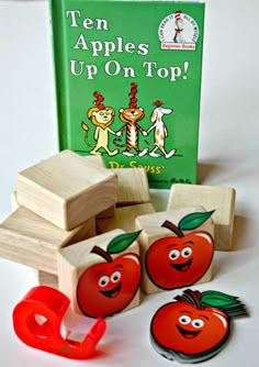 an apple and two wooden blocks with the book ten apples up on top by dr seuss