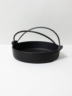 an empty black cast iron skillet on a white surface with the handle extended up