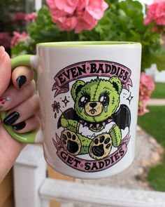 a woman holding a green and white coffee mug with an image of a teddy bear on it