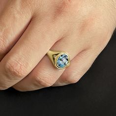 a person's hand with a ring on it and a blue stone in the middle