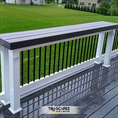 a white bench sitting on top of a wooden deck next to a lush green field