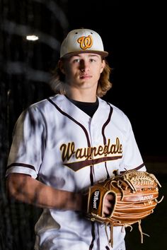 a young man in a baseball uniform holding a catchers mitt