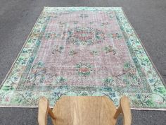 an old rug is laying on the ground with a wooden chair in front of it